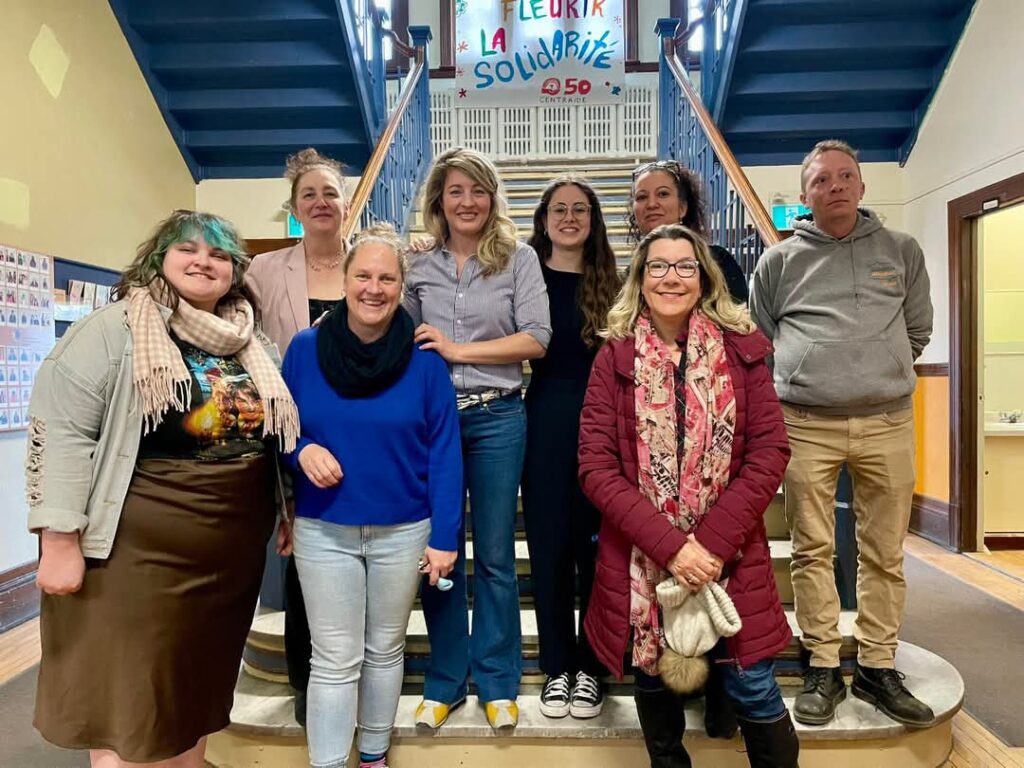 Mélanie Joly au centre sur la rue Laverdure au milieu de représentants du milieu communautaire. 